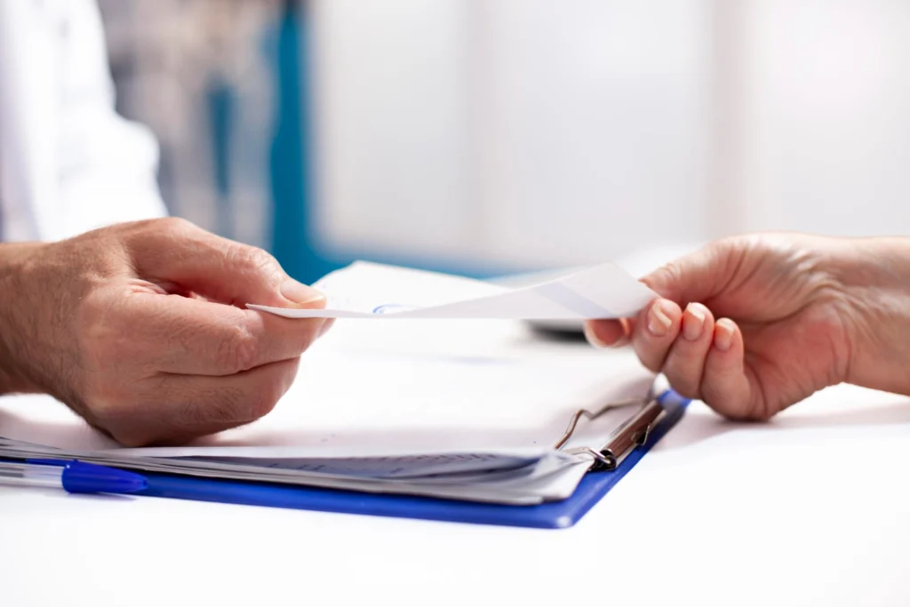 Person handing over patent transfer documents to another person, illustrating patent licensing and ownership transfer in India.