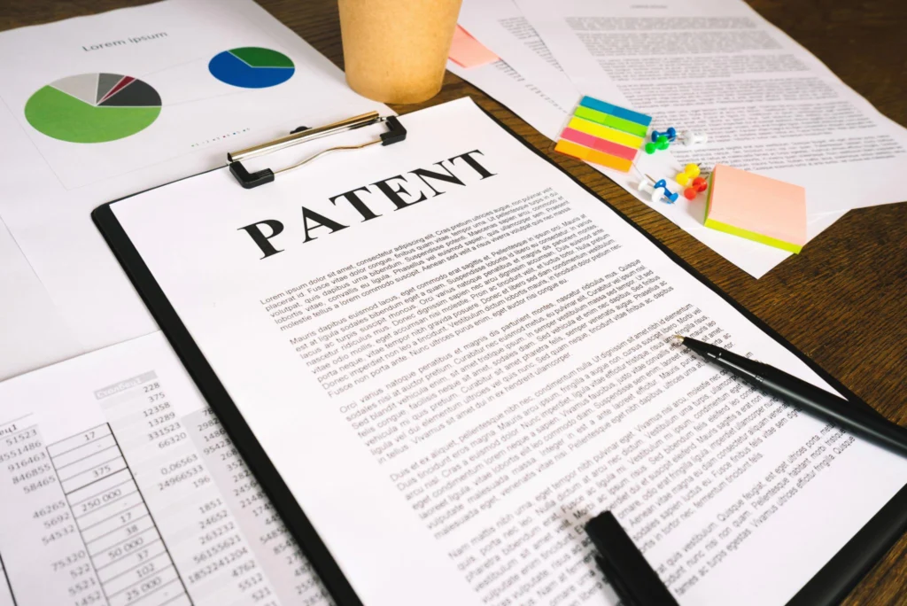 A clipboard featuring a legal document with the word PATENT printed at the top, placed next to business charts and legal paperwork explaining Section 60 of the Patents Act 1970 regarding the restoration of terminated patents.