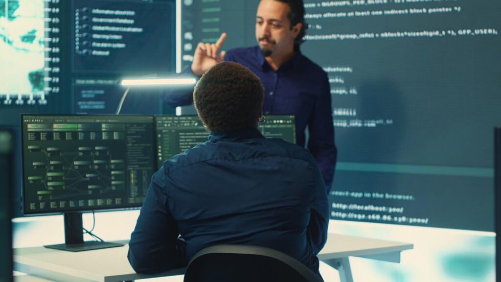 Two software developers collaborating in front of code screens to secure software through copyrights.