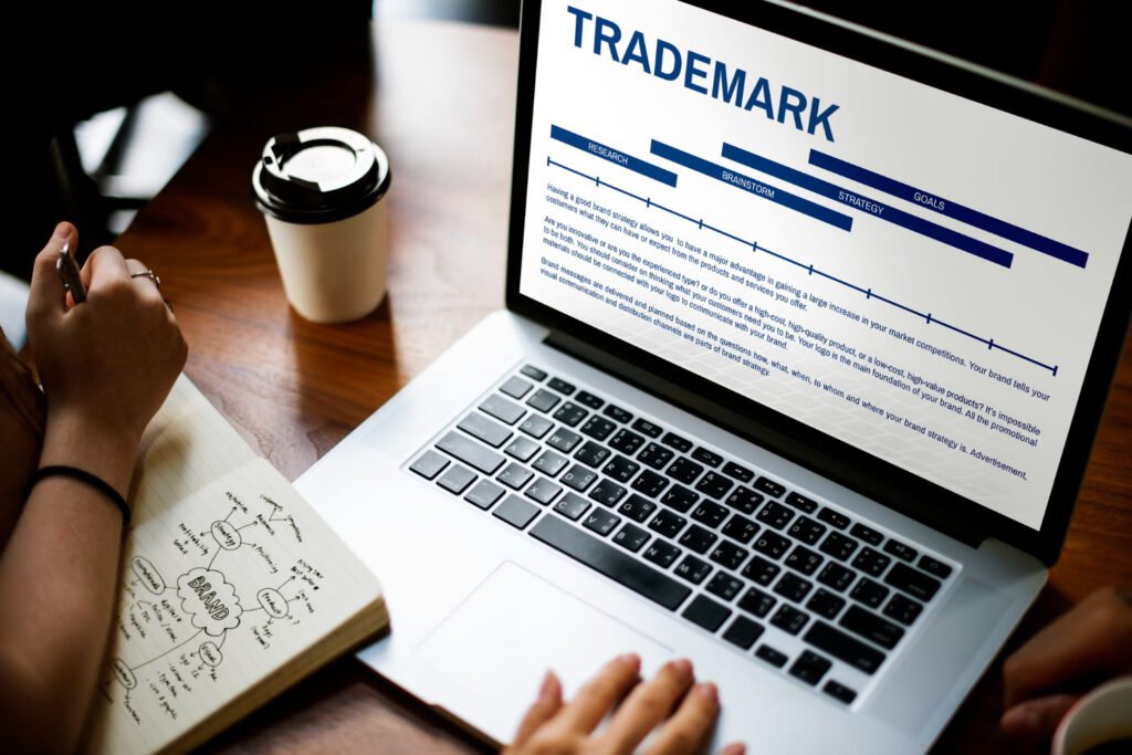 A person researching trademark law on a laptop next to a notepad discussing brand strategy and identical trademarks.