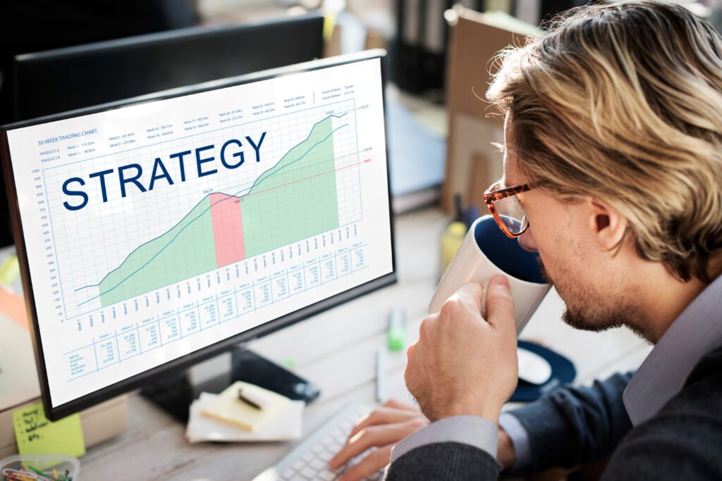 Professional looking at a strategy graph on a computer screen while drinking coffee.