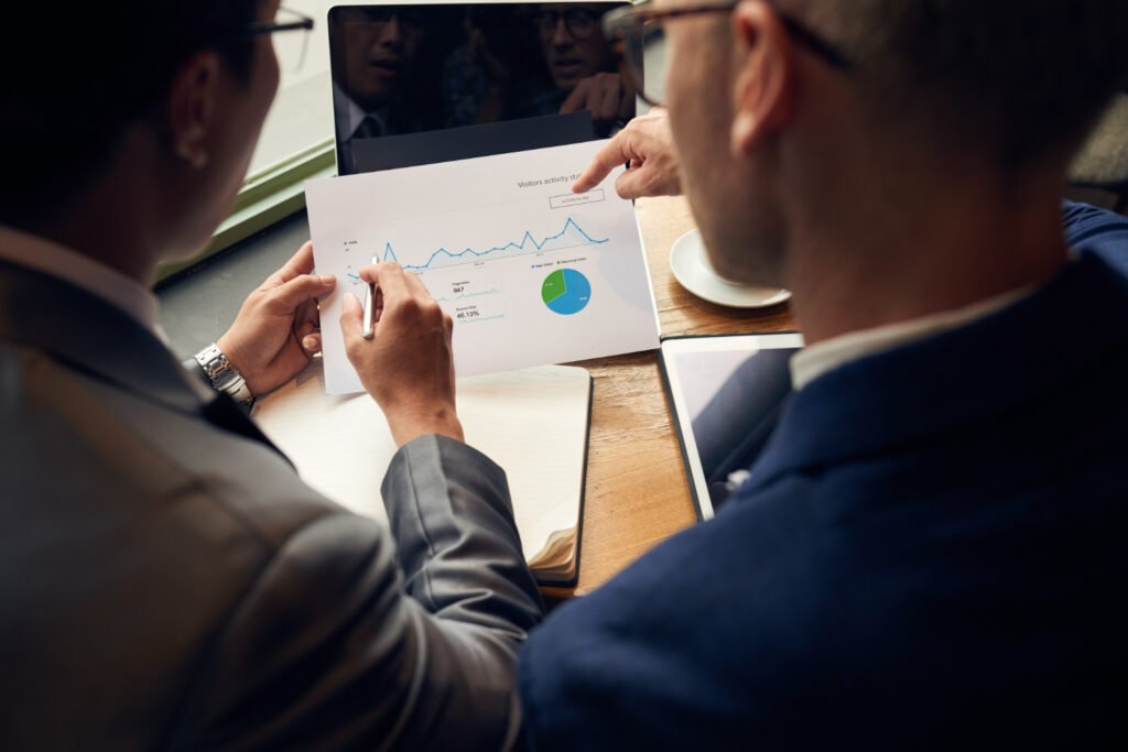Two venture capitalists analyze a data report on a tablet and paper, discussing charts and graphs related to a startup's intellectual property portfolio